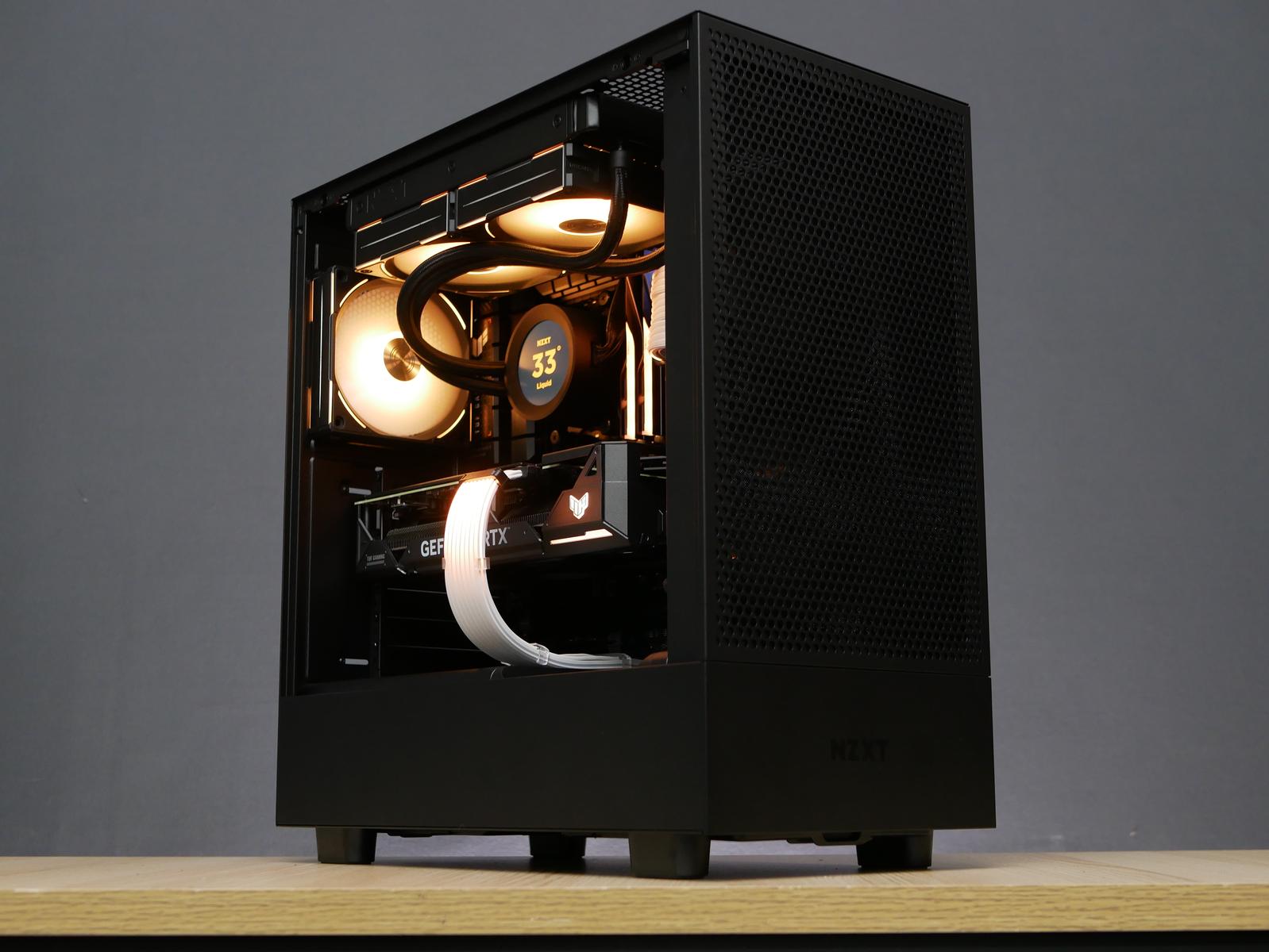 A Tarmangie build on the bench: black mesh case, warm-lit liquid cooler and white braided power cables.